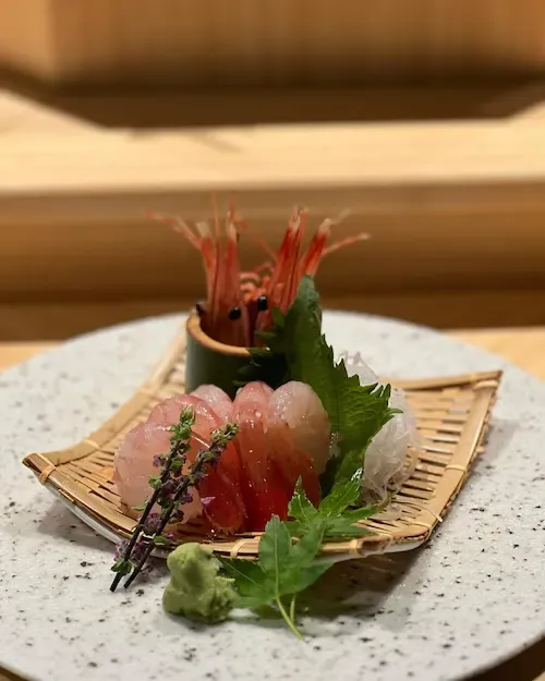 Ebi sashimi decorated with prawn head and greens